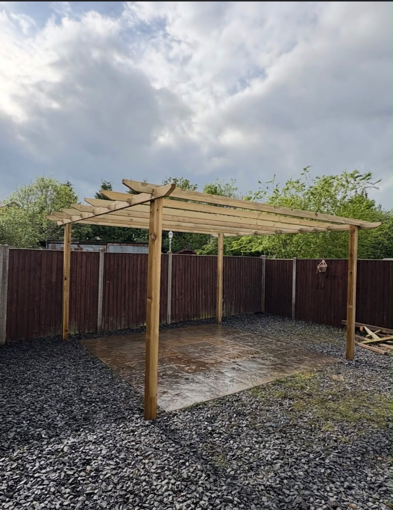 New timber pergola over a slate patio with fresh gravel after landscaping